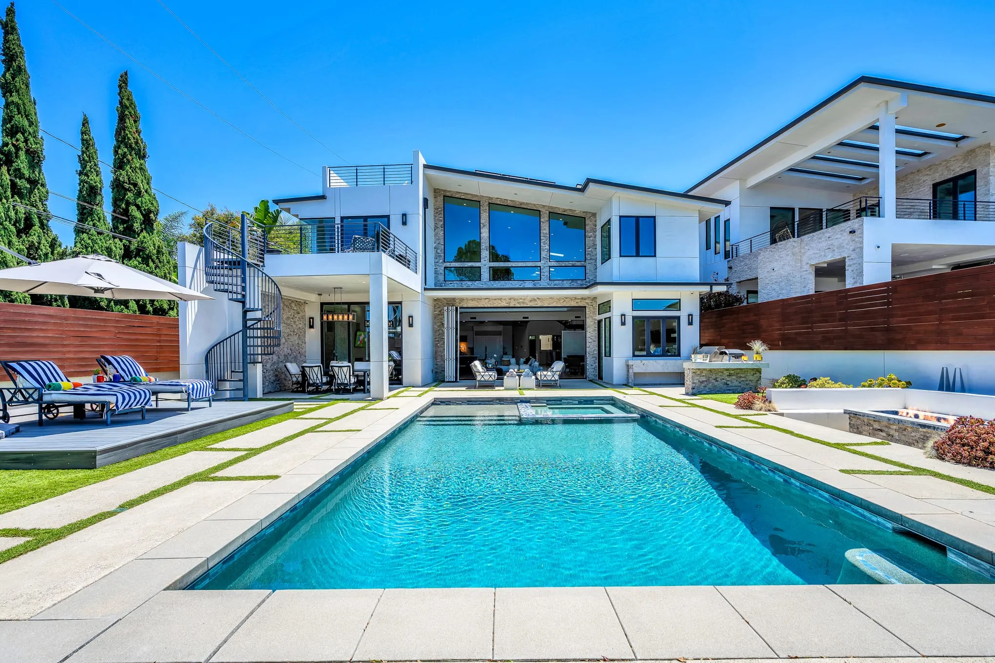 The full-length pool, spa, and expansive backyard framed by the modern home