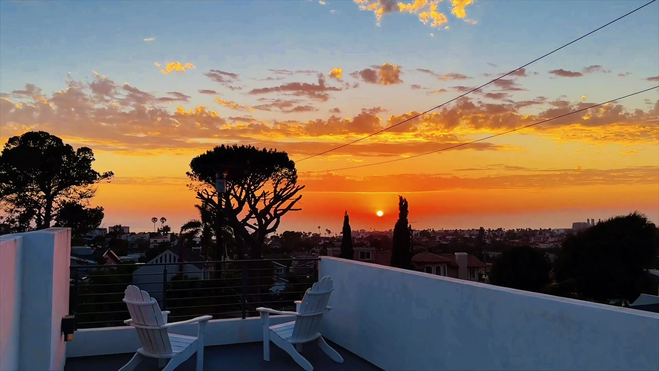 Golden-hour sunset over the coastline, seen from the private rooftop deck